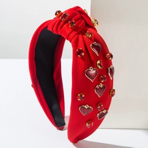 Detail eines roten geknoteten Stirnbands mit Glitzerherz-Anhängern und Strassverzierung