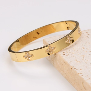 Polished gold stainless steel bangle with flower-shaped zircon inlays and side clasp