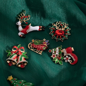 Set of 5 Christmas enamel brooches with reindeer and bells on green satin background