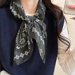 Close-up of dark green silk scarf with retro geometric patterns around the neck