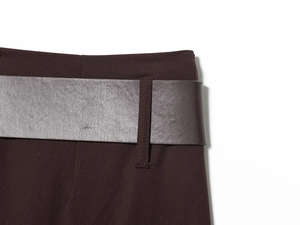 Detailed close-up of dark chocolate trousers featuring a faux leather belt and woven fabric