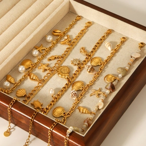 Gold stainless steel ocean-themed bracelet with sea shell and starfish charms in a box