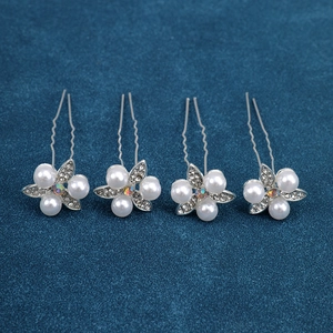 Close-up of four floral U-shaped hair pins with white pearls and sparkling rhinestones