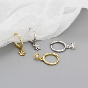 Macro shot of gold and silver star drop earrings featuring hollow stars and zircons