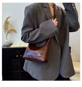 Detail of embossed lettering on dark brown leather shoulder bag with a sleek finish