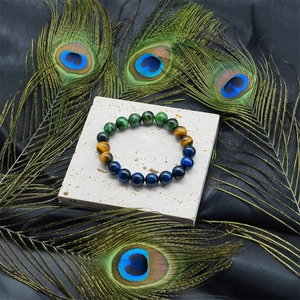 Tiger eye and malachite stone beaded bracelet on slate with peacock feathers