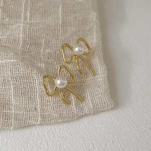 Elegant 925 sterling silver bow knot earrings with pearls on beige fabric background