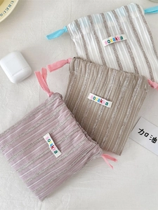 Vertical striped drawstring organizers in lavender, khaki, and beige canvas material