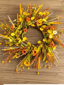 Détails d'une couronne d'automne artificielle avec tournesols et baies sur bois clair