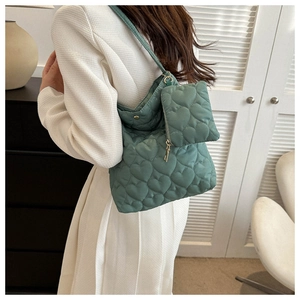Detail of green heart-quilted tote bag featuring a matching mini coin purse and strap