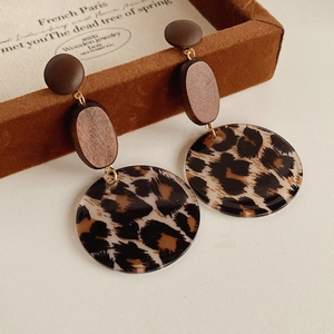 Close-up of leopard print resin earrings with wooden studs on a vintage jewelry box