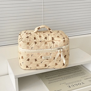 Dettaglio della borsa da trucco beige trapuntata con motivi di orsi e nastro sulla cerniera