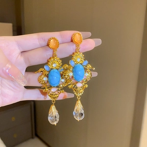 Close-up of vintage gold earrings with blue turquoise, orange beads and crystal drops