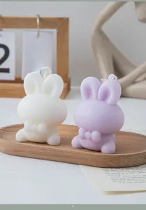 Detail of bunny scented candles in white and lilac with bow relief on a wooden tray