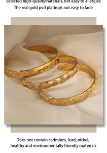 Close-up of gold celestial engraved cuff bracelets with crystals on white silk background