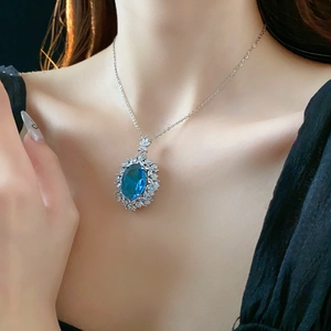 Close-up of elegant silver necklace with oval blue gemstone and zircon floral pendant