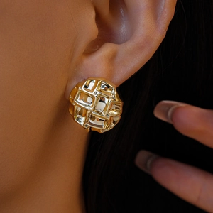 Gros plan d'une boucle d'oreille carrée dorée avec texture gaufrée sur un mannequin