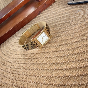 Close-up of gold H-shaped quartz watch featuring leopard print and mesh steel strap