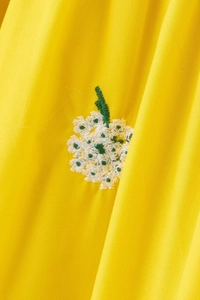 Close-up of fabric texture with white and green floral embroidery on yellow fabric