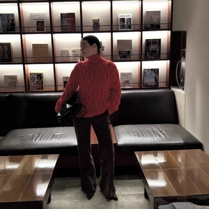 Chic red cable knit turtleneck sweater for women paired with brown trousers and black bag