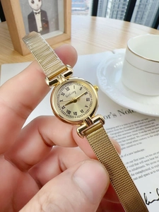 Close-up of vintage gold women's quartz watch with Milanese mesh band and Roman numerals