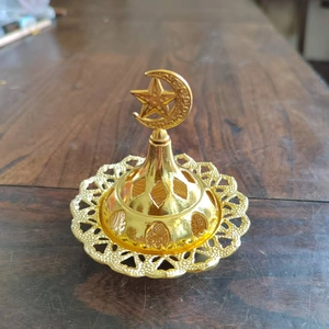 Close-up of golden Middle Eastern incense burner with hollow geometric patterns and star moon lid