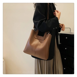 Dettaglio di una borsa tote vintage in pelle marrone con texture opaca e fibbia in metallo