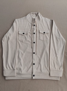 Detailed view of beige corduroy jacket texture featuring black buttons and front flap pockets
