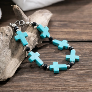 Men's fashion turquoise cross bracelet with black beads on a rustic wooden surface