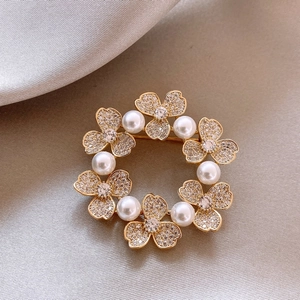 Macro detail of a 14k gold plated wreath brooch with pearls and sparkling rhinestones