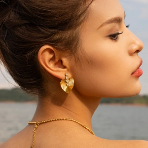 Detail of vintage heart-shaped gold earrings with embossed texture and zircon accents