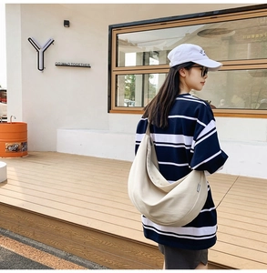 Outdoor lifestyle shot of a model wearing a beige large capacity oxford crossbody bag