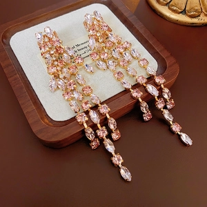 Elegant gold-tone tassel earrings featuring pink and clear rhinestones on wood display