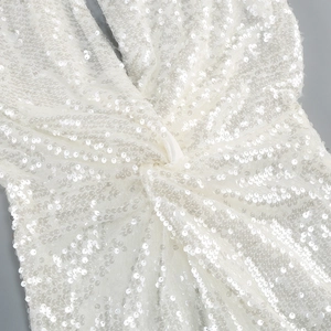 Detailed macro view of white sequin fabric with elegant cross-knot design and sparkling finish