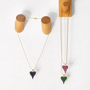 Détail de pendentifs en cœur colorés sur d'élégantes chaînes à billes dorées avec fermoirs