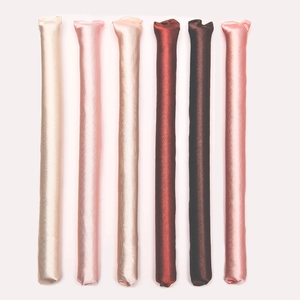 Detailed view of six colorful satin heatless hair curlers in champagne and pink tones