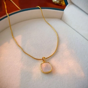 Detail of square pink mother of pearl pendant on golden snake chain necklace