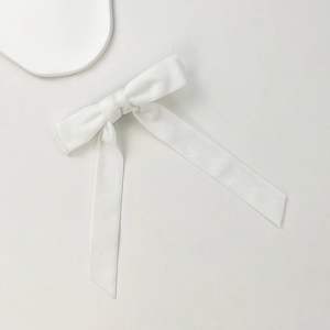Dettaglio del fiocco in raso bianco con nastro elegante su uno sfondo bianco pulito