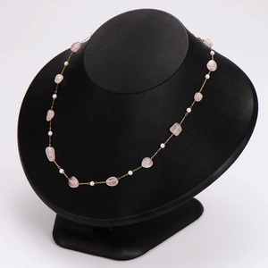 Gold stainless steel necklace with pink gemstones and white beads on a black mannequin