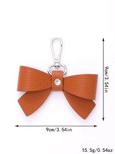 Brown leather bow keychain with silver hook showing dimensions 9cm by 9cm and 15.5g weight