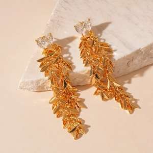 Detailed macro view of gold leaf fringe earrings with heart-shaped zircon stones