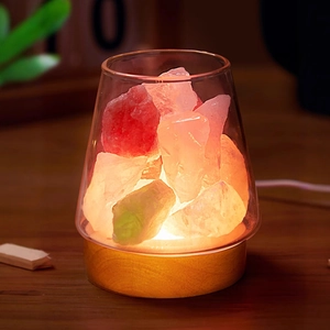 Detailed view of colorful crystal stones inside a clear glass jar with a warm wooden base