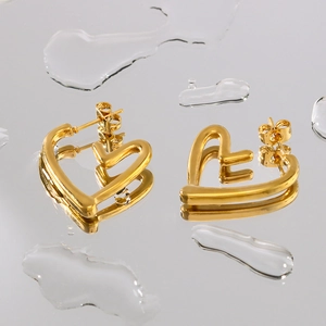 Polished 18K gold stainless steel hollow heart earrings on a reflective water surface