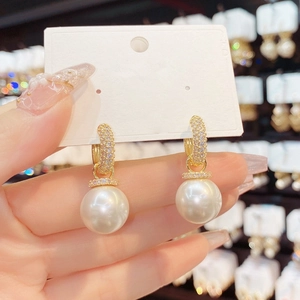 Detail of long pearl tassel earrings with gold cubic zirconia hooks held by hand