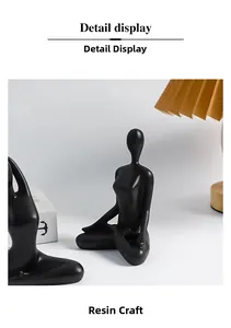 Detail of matte black resin yoga figurines set against a white wall with lamp