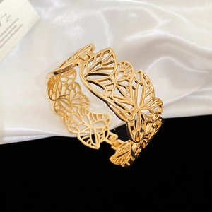 Detailed macro of gold hollow butterfly bracelet with a side hinge clasp on silk