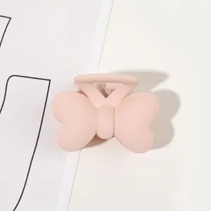 Macro shot of matte pink butterfly hair claw clip with a frosted finish on white background