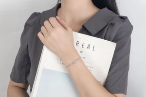 Detailed view of an elegant silver heart bracelet with cubic zirconia on a female wrist