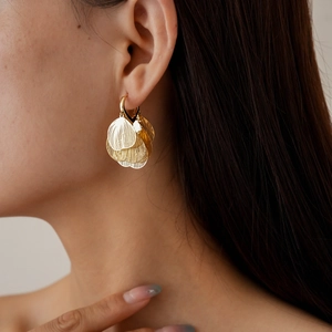 Detailed close-up of gold hollow heart petal earrings worn by a model in soft lighting