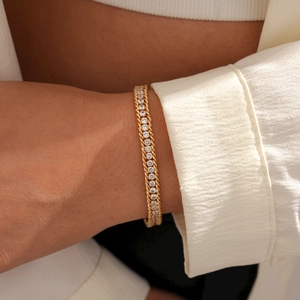 Close-up of golden tennis bracelet with round cubic zirconia on model wrist